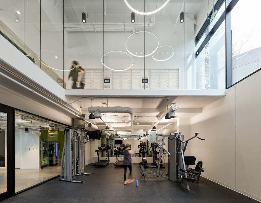 Blurred figures in motion in a two-story, glass-walled gym