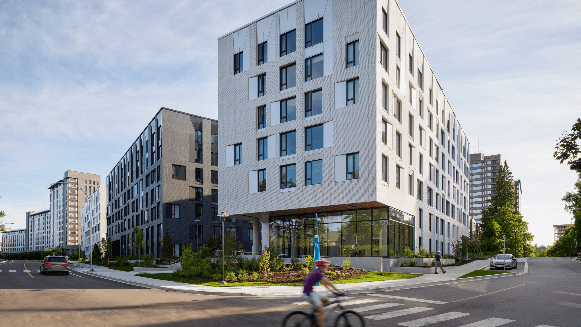Exterior photo of the building project in daylight with cyclist riding past in blur of motion