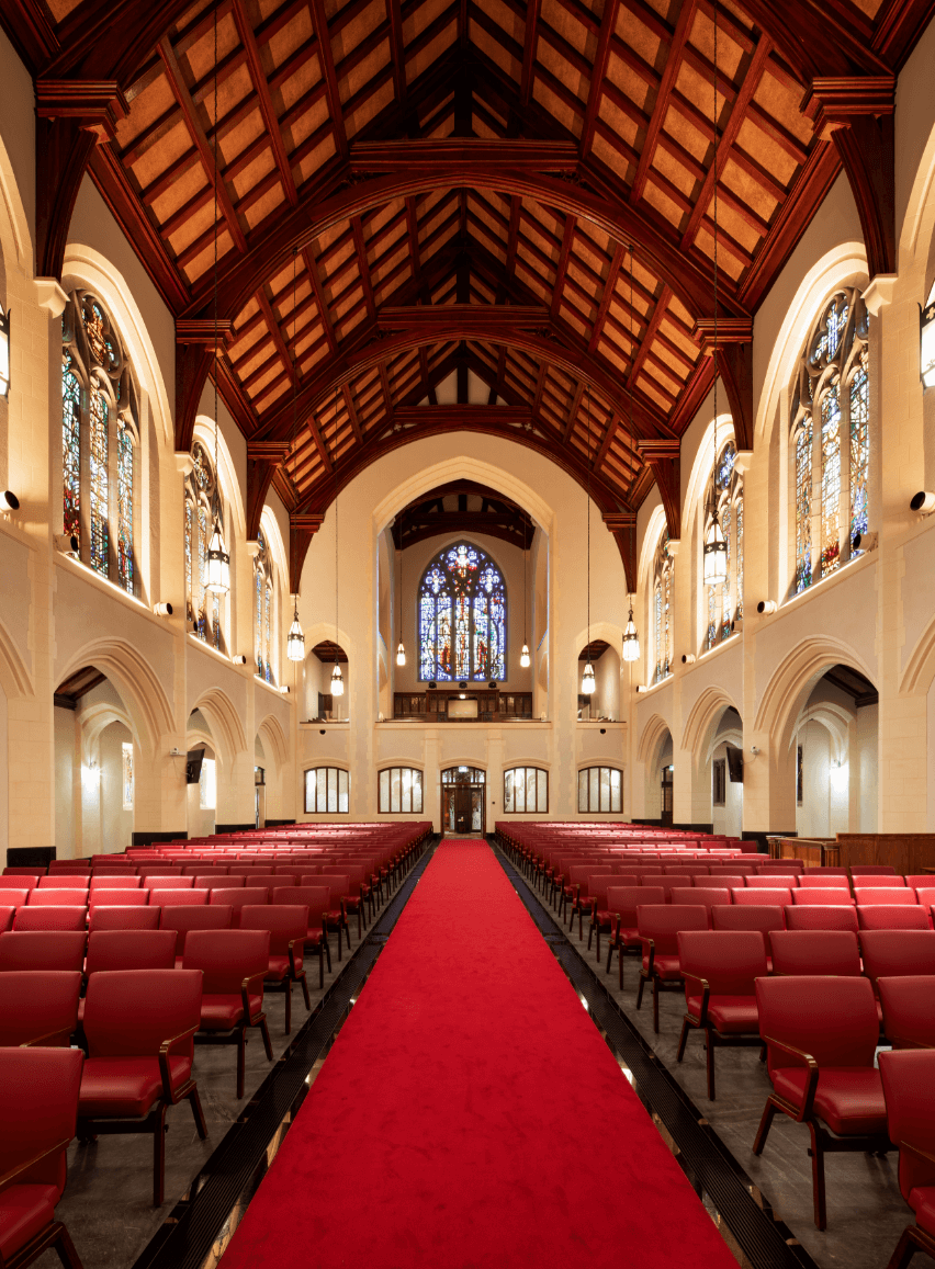 Looking down the red carpeted nave of the church towards the altar, with pews either side